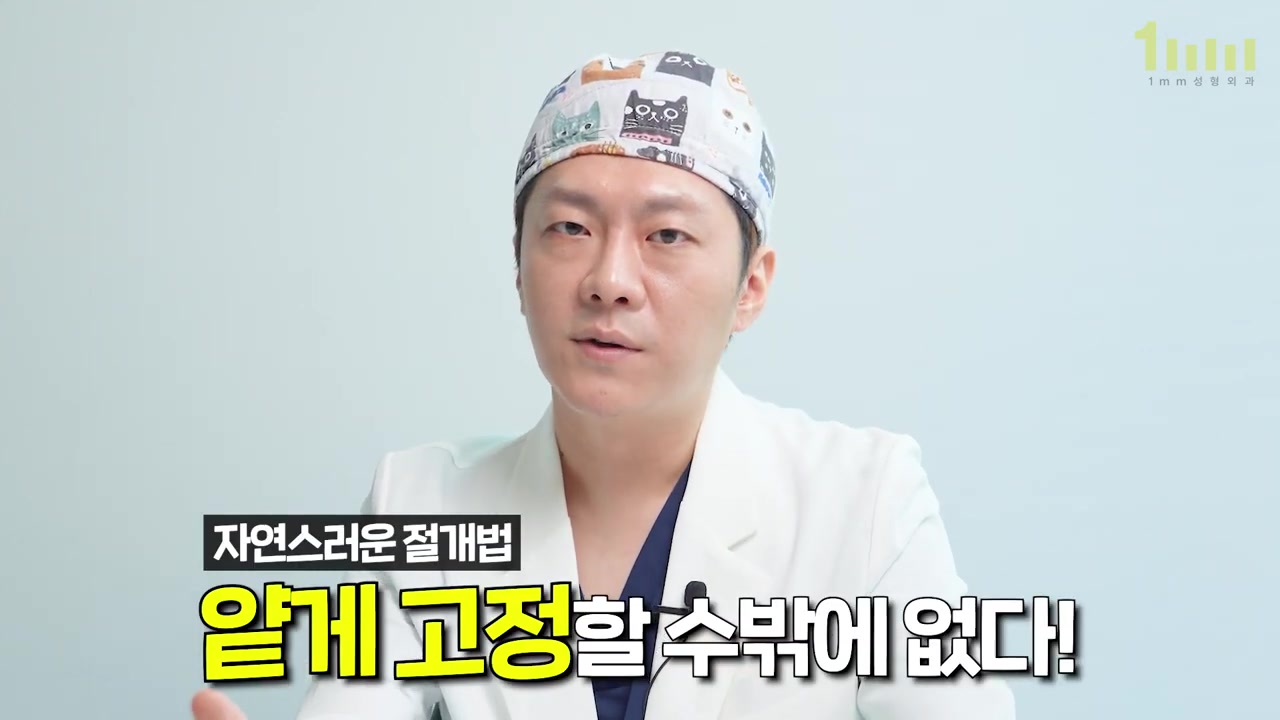 수술모를 쓴 의료진이 설명하고 있고, 화면 아래에 ‘자연스러운 절개법’ 이라는 작은 제목과 ‘얕게 고정할 수밖에 없다!’ 라는 자막이 놓인 영상 화면