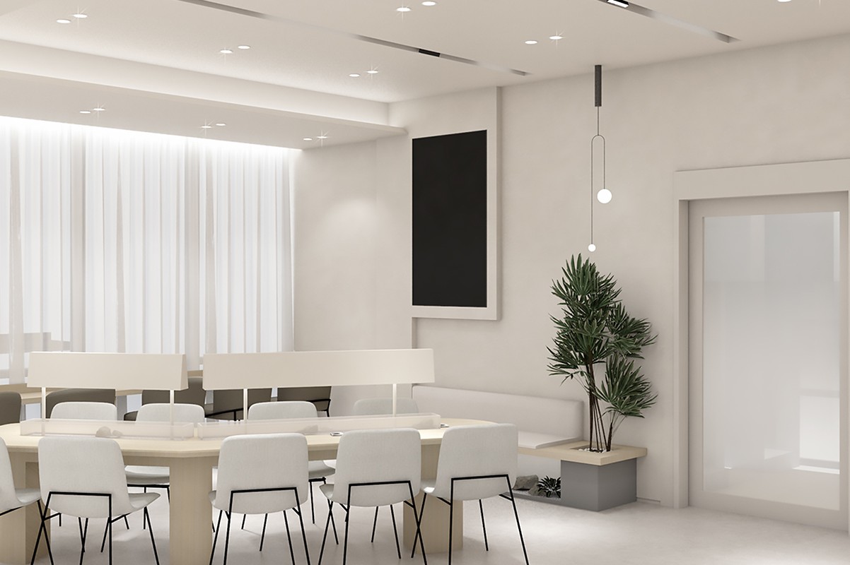An interior image of a space with a tall window draped in white curtains, a long wooden table, white chairs, and a potted plant.